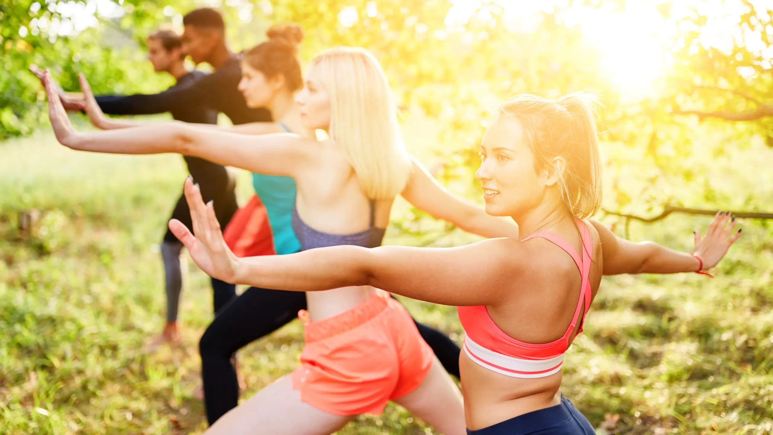 Group of friends doing tai chi together in fitness class in nature in summer