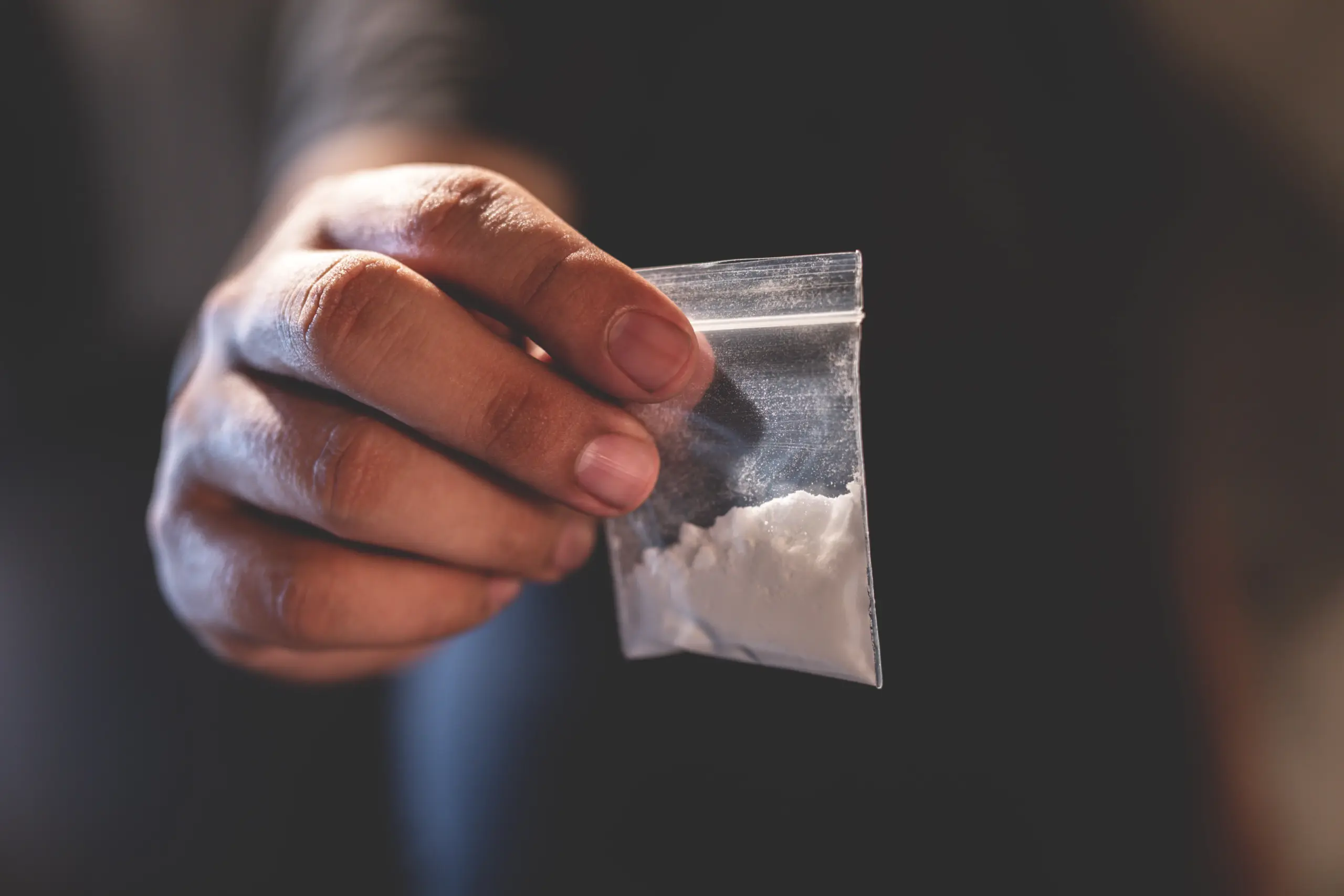 Man hand holds plastic packet or bag with addict narcotics cocaine powder or another