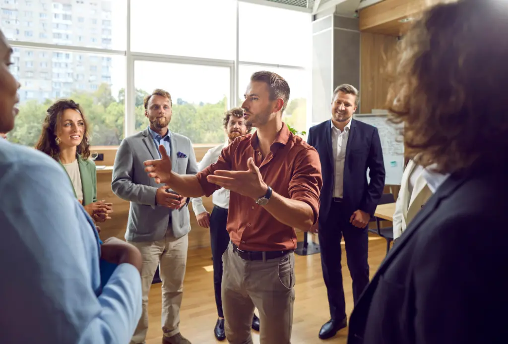 Young male business trainer or psychologist standing in a circle of men and women