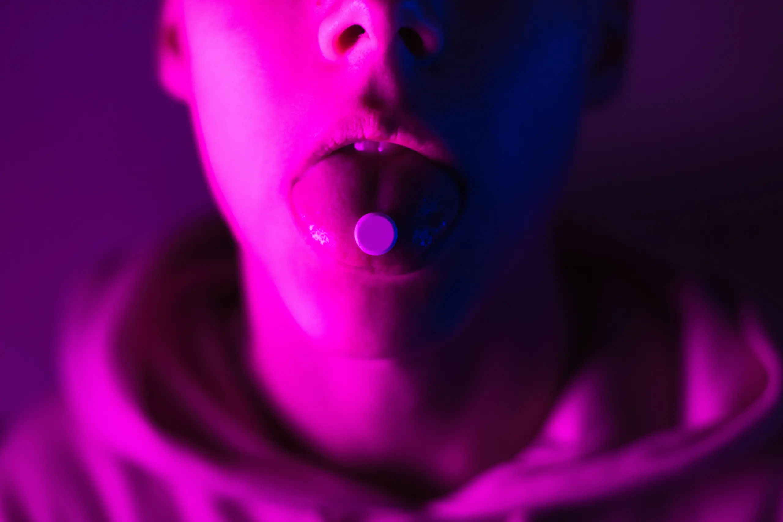 Young teenager in a pink hoodie takes a drug in pills. Tongue guy with lsd wheel